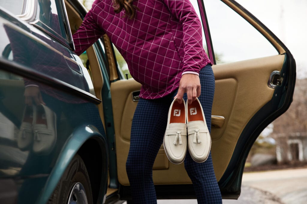 A woman gets into a car holding a pair of golf shoes. Strong example of a product photographer in Los Angeles.