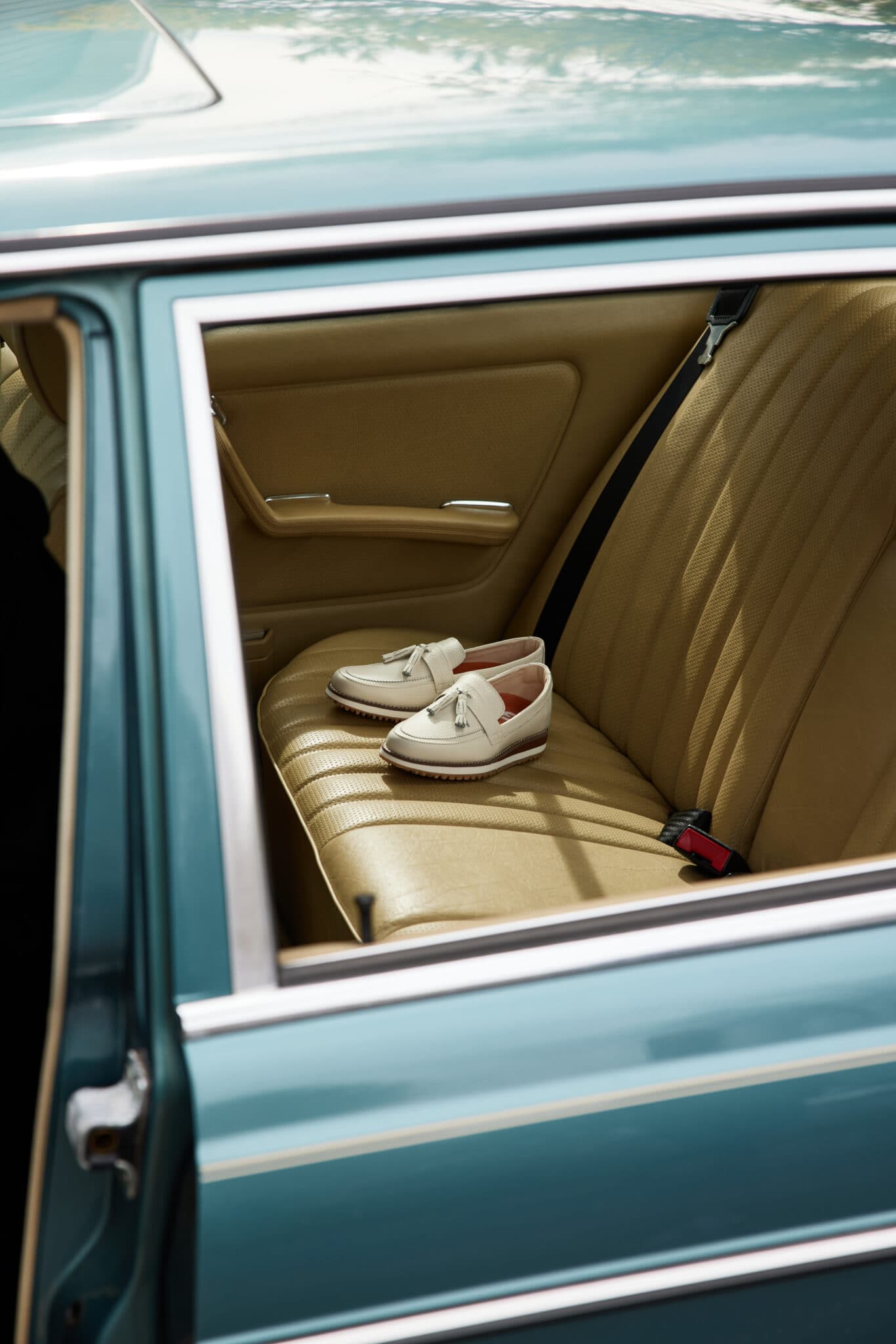 A pair of golf shoes placed on the seat inside of a vintage vehicle.