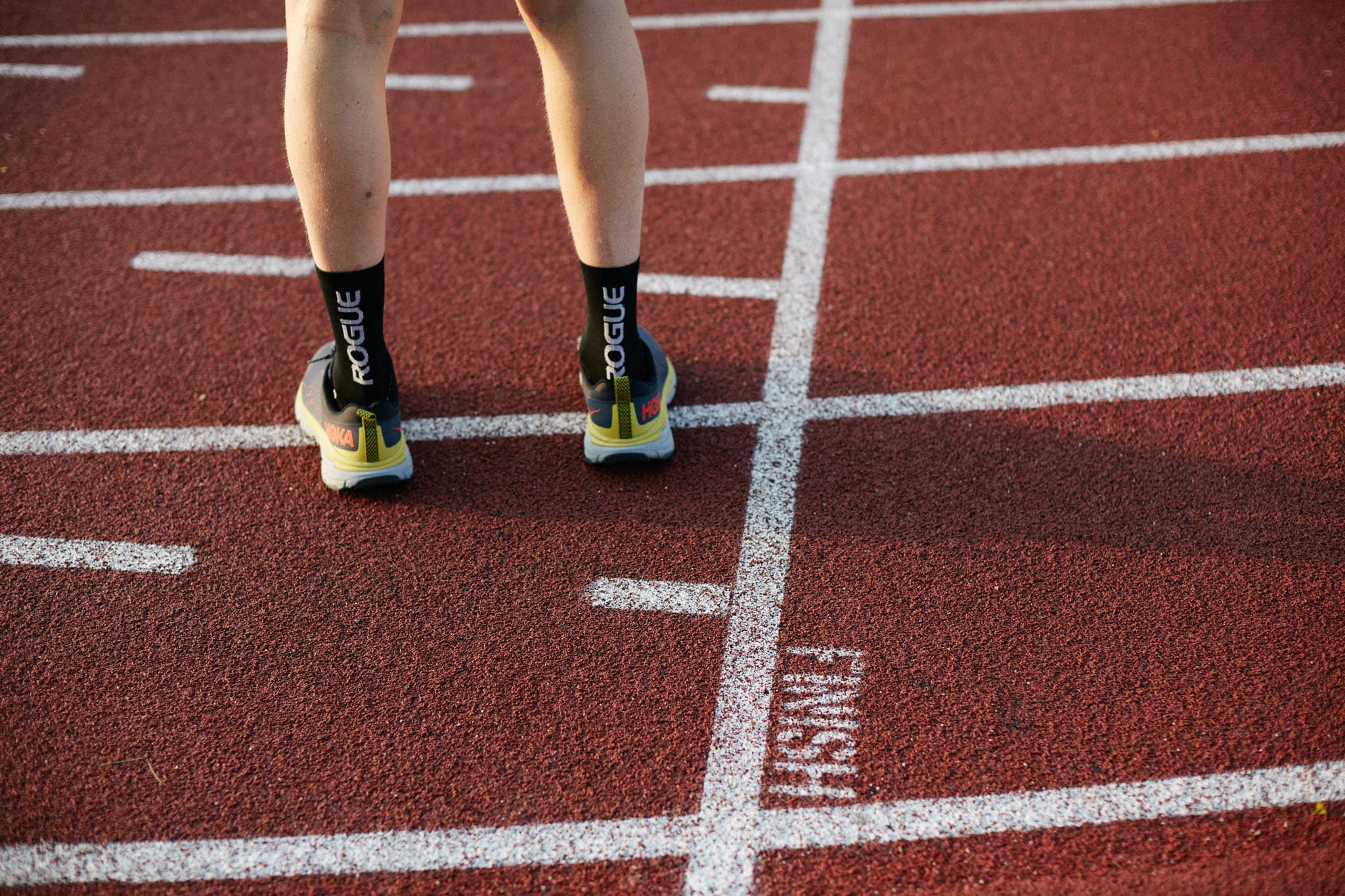 Close up of a runner's feet facing away standing on an outdoor running track. Image taken by Los Angeles advertising photographer.