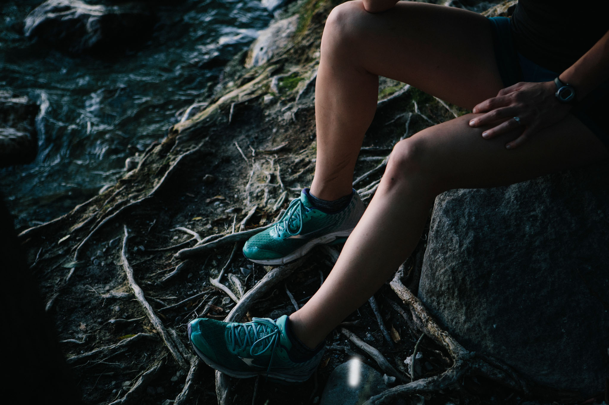 Los Angeles fitness photographer takes a picture of a trail runner rests by a stream.