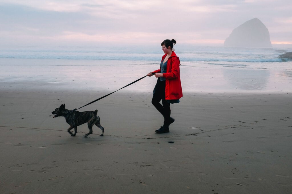 Woman in red jacket walking her dog on the beach, shot by lifestyle photographer located in Los Angeles