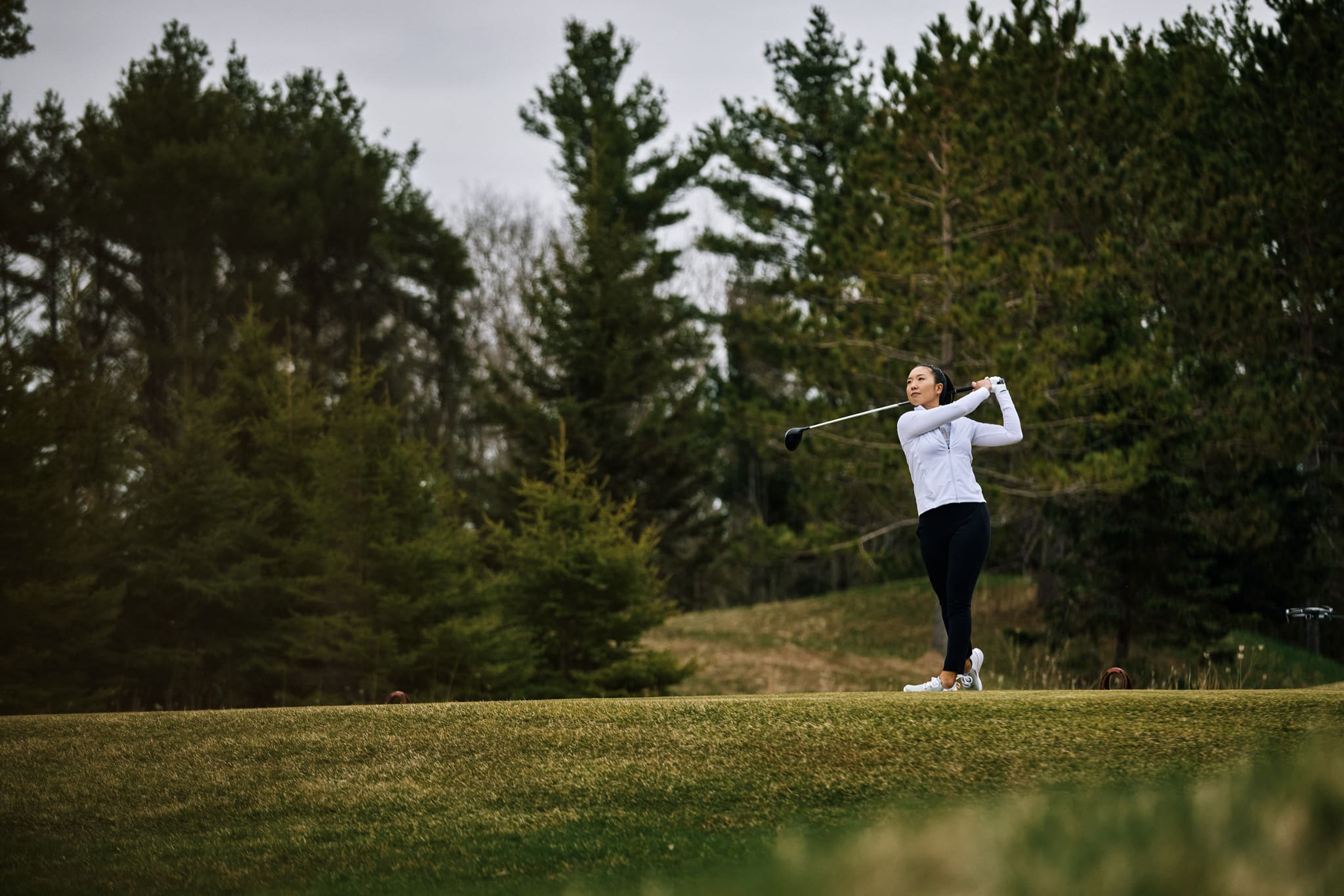 a woman swings a golf club on a golf course
