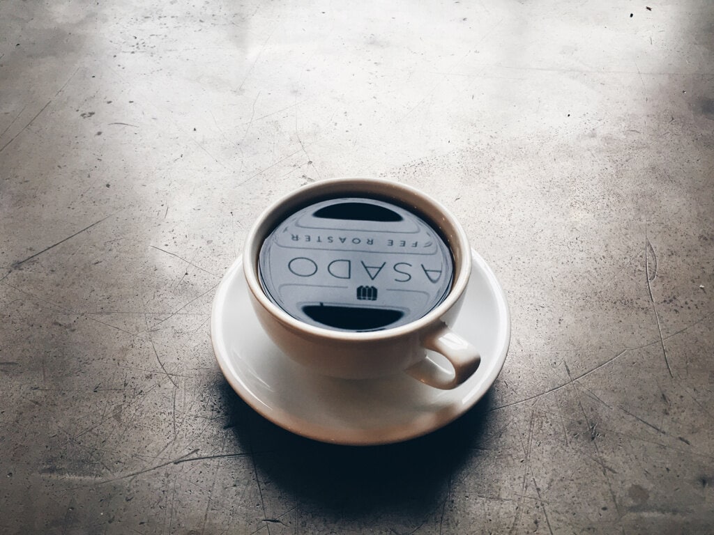 cup of coffee on concrete table with coffee shop name reflected in cup