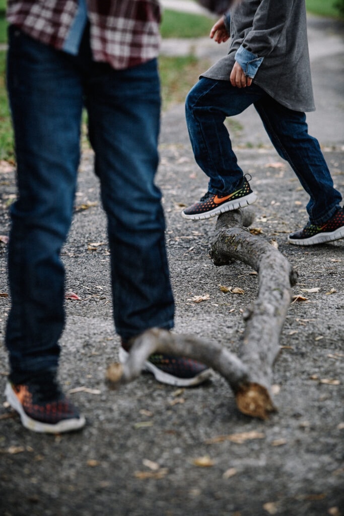 Close up of children's feet playing with sticks on the ground, taken by lifestyle photographer Hannah Dunsirn.