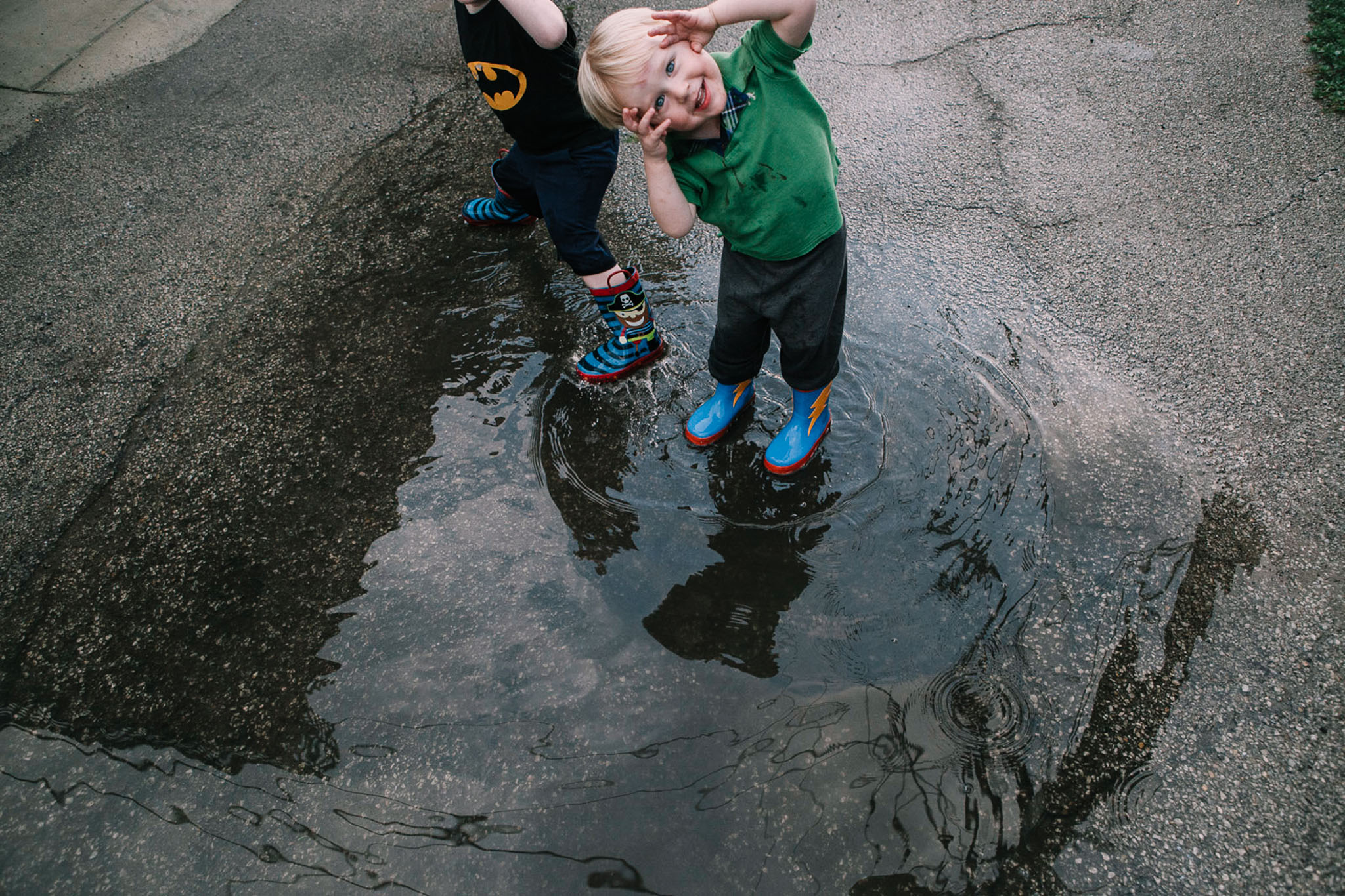 Lifestyle image of a child standing in a puddle playfully gazing at photographer in LA