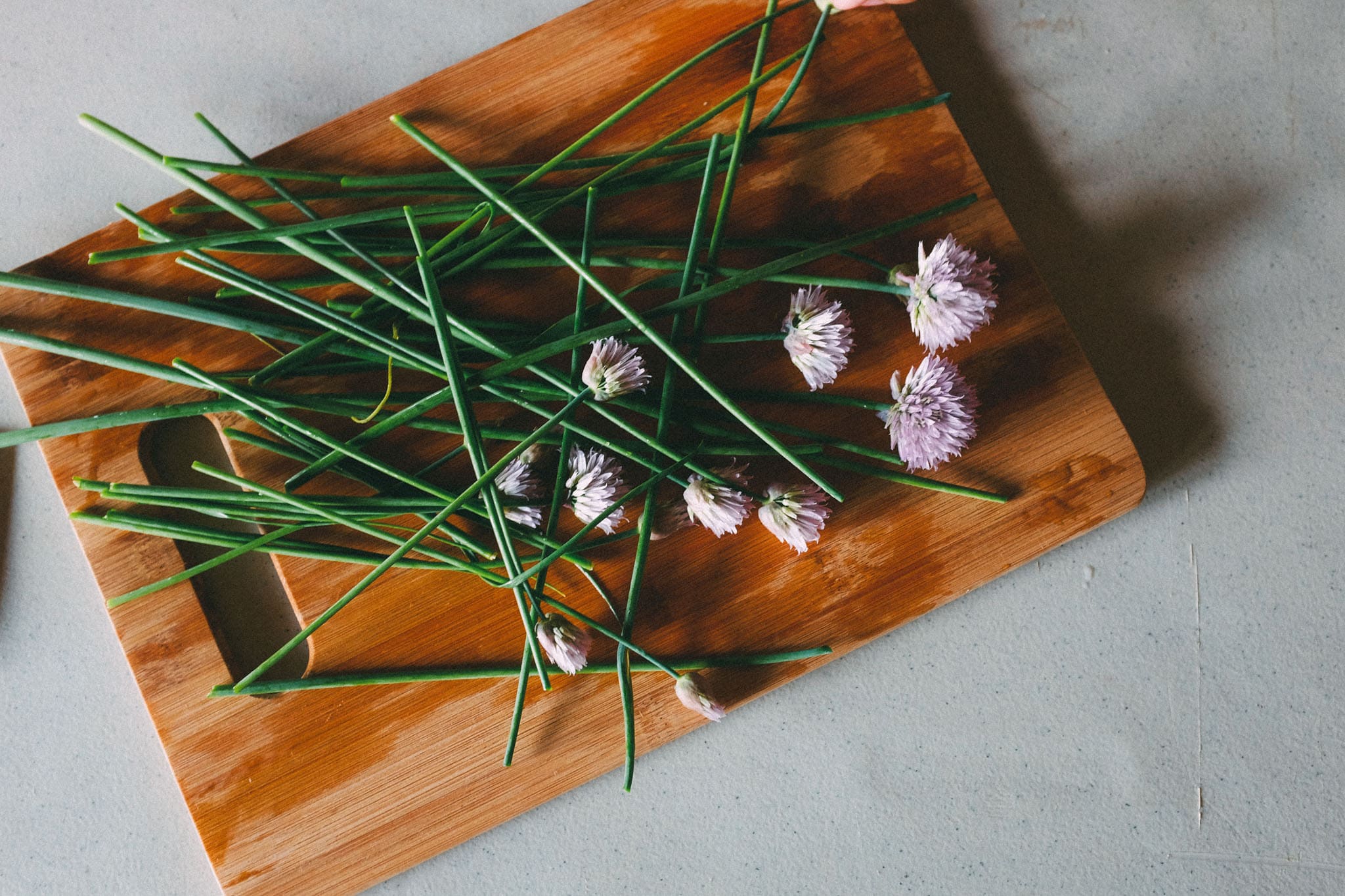 fresh stems and purple flowers placed on a wooden cutting board taken by a commercial lifestyle photographer
